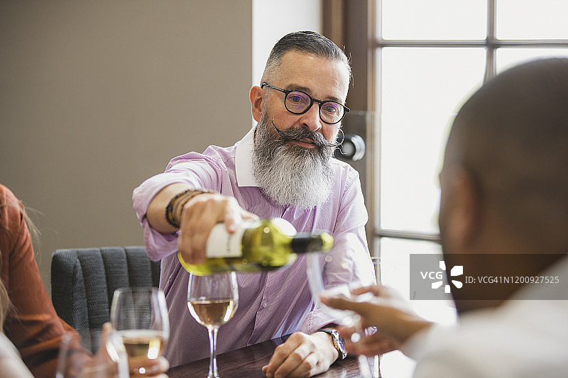 下班后为朋友倒酒的时尚胡须男图片素材