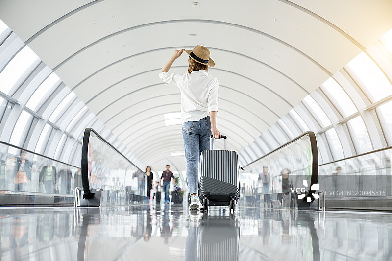 年轻女子身穿休闲装，走在机场大厅里图片素材