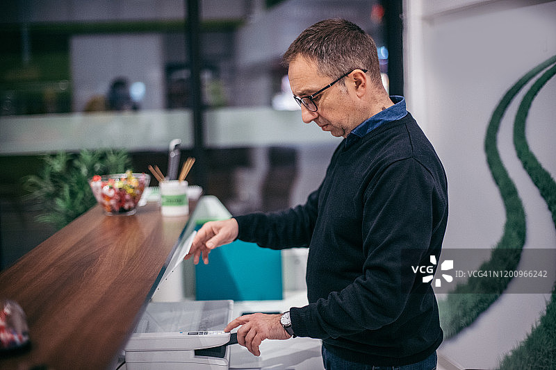 在办公室使用打印机的中年男人图片素材