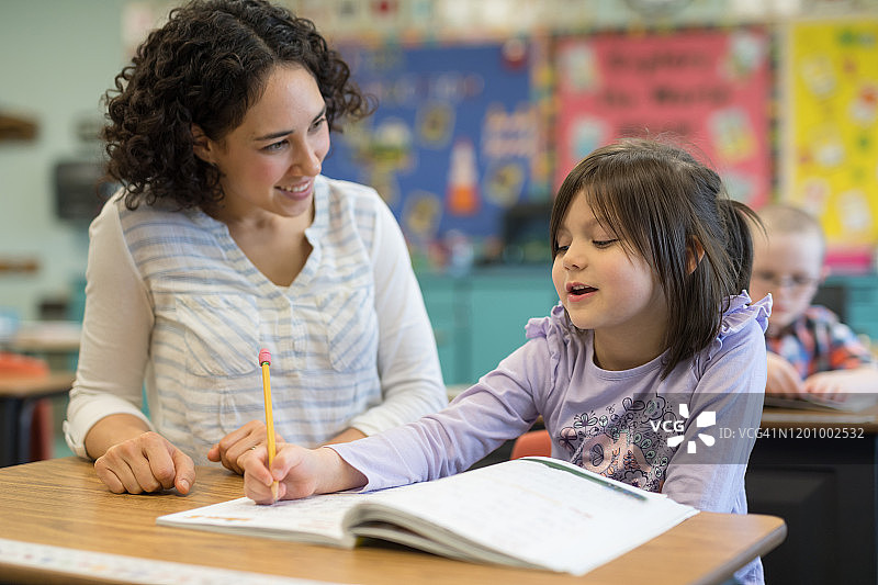 一年级女生在教室里和老师交谈图片素材