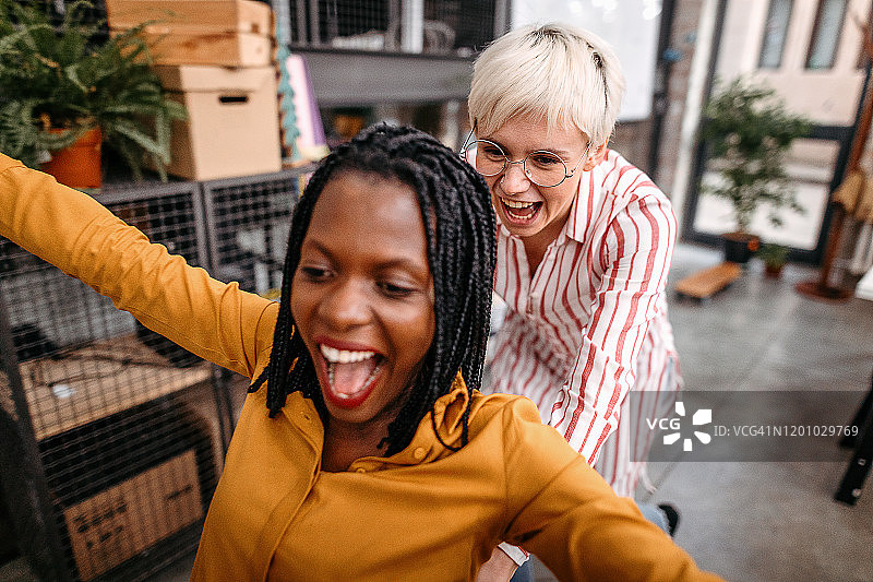 女商人们在办公室享受椅子比赛。图片素材