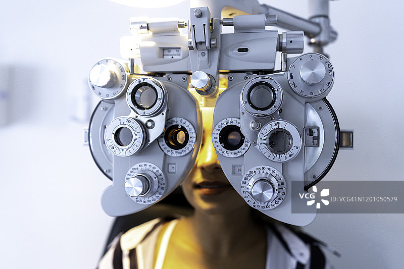 女士在眼科诊所用光学焦度计测量视力图片素材