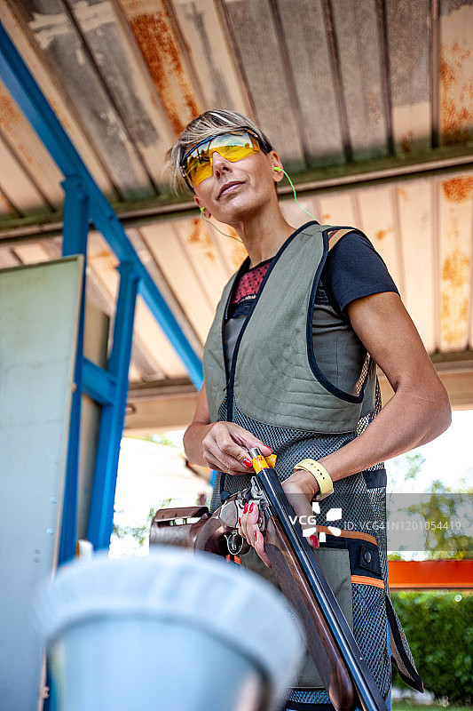 成年女射手装填猎枪并眺望远方的低角度肖像照片图片素材