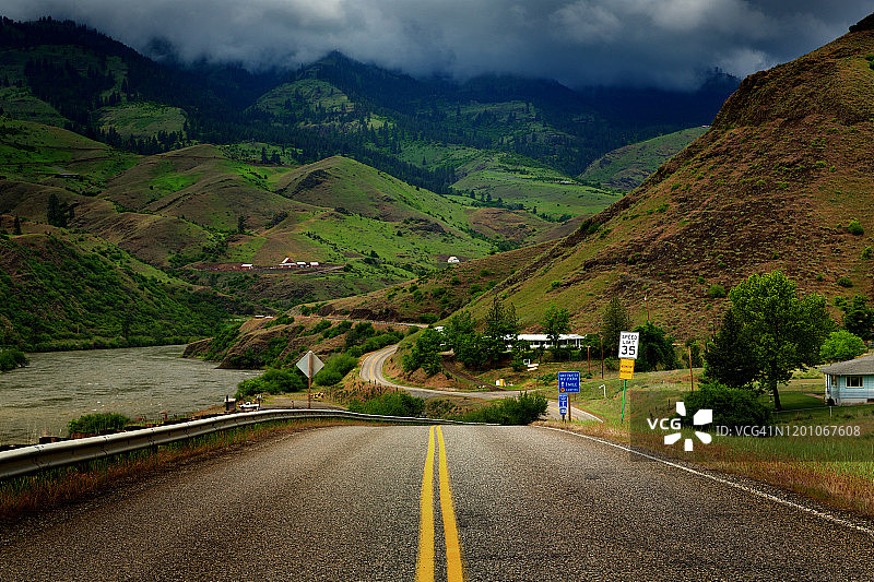 爱达荷州白鸟镇萨蒙河外，暴风云下的乡村道路双黄线图片素材