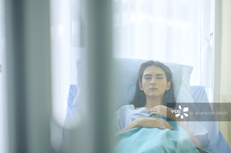年轻女患者躺在医院病房的病床上，医学与健康护理概念图片素材