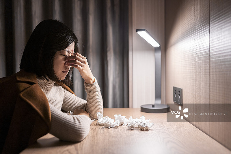 年轻女子坐在桌前捂着鼻子图片素材