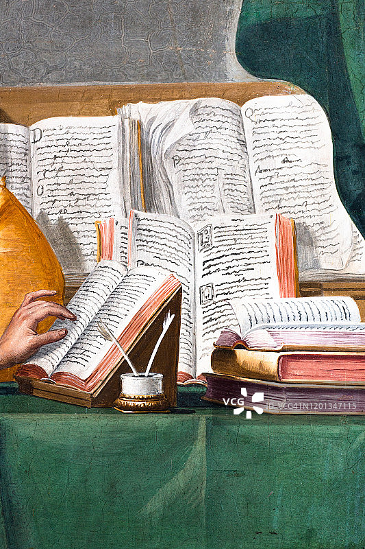 修复后的十七世纪壁画细节：手跟随打开的书本上的文字，书桌上有墨水和羽毛笔等书写工具图片素材