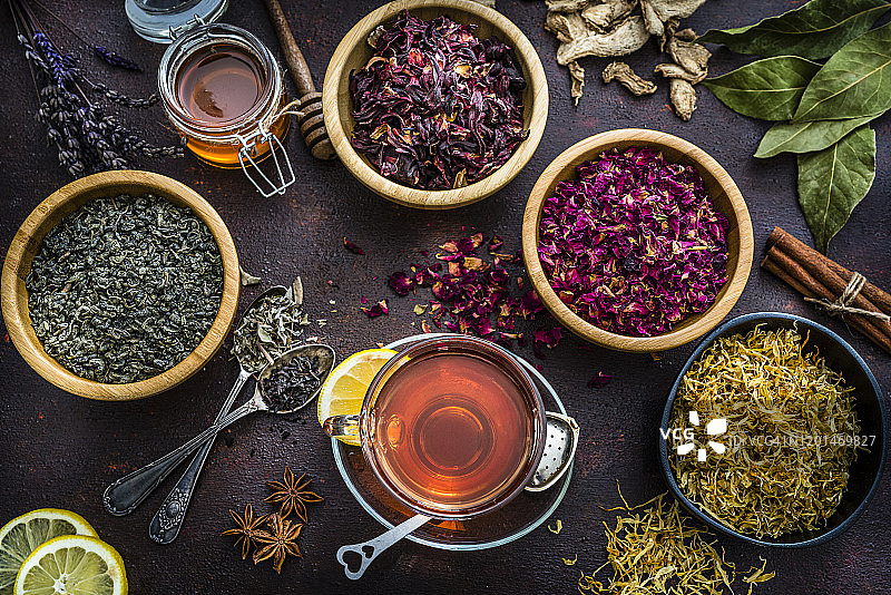 棕色桌子上俯视拍摄的茶叶与花草茶杯图片素材