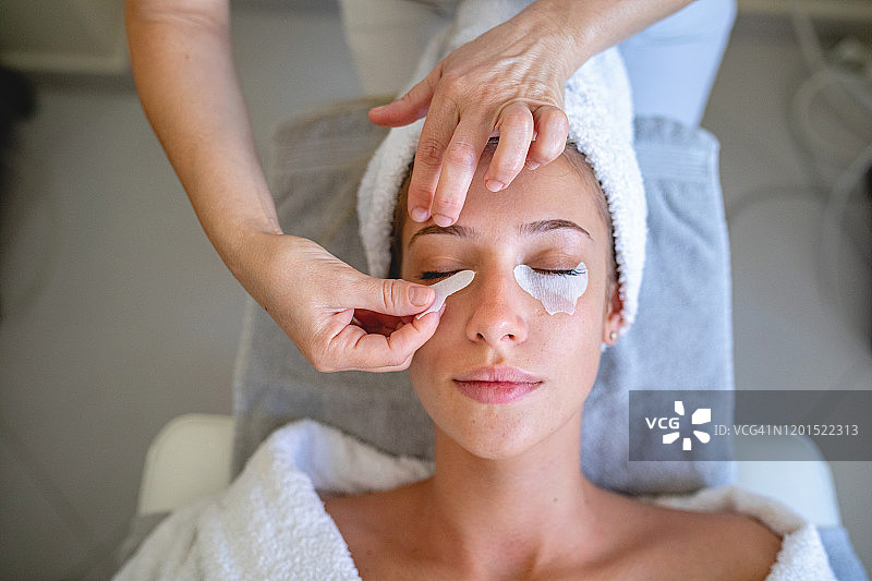 美容师为年轻美女眼部下方贴眼膜图片素材