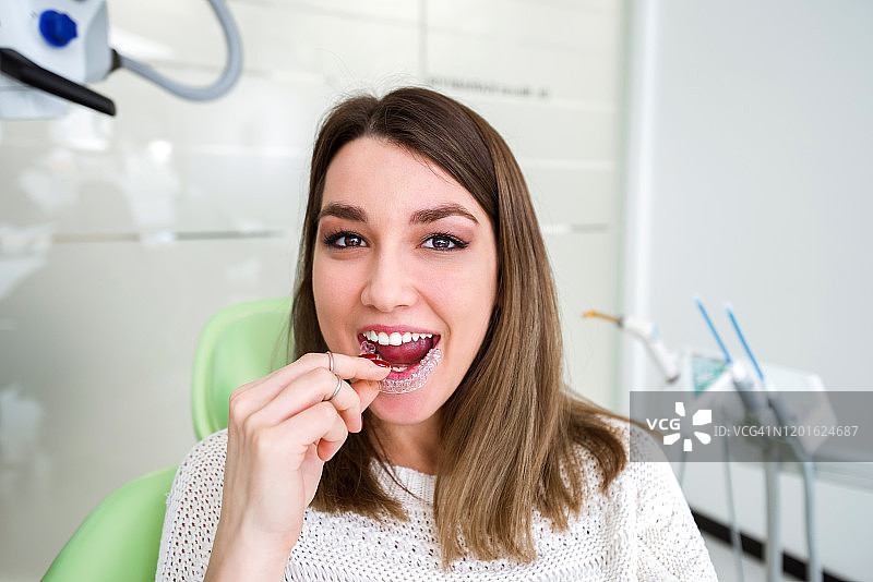 女人在牙科诊所拿着正畸保持器图片素材