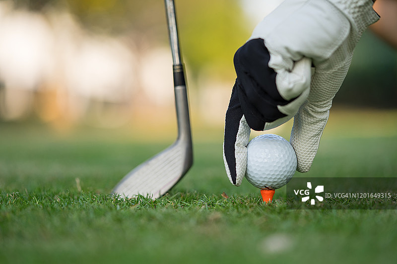 手将高尔夫球放在高尔夫球场的球座上图片素材