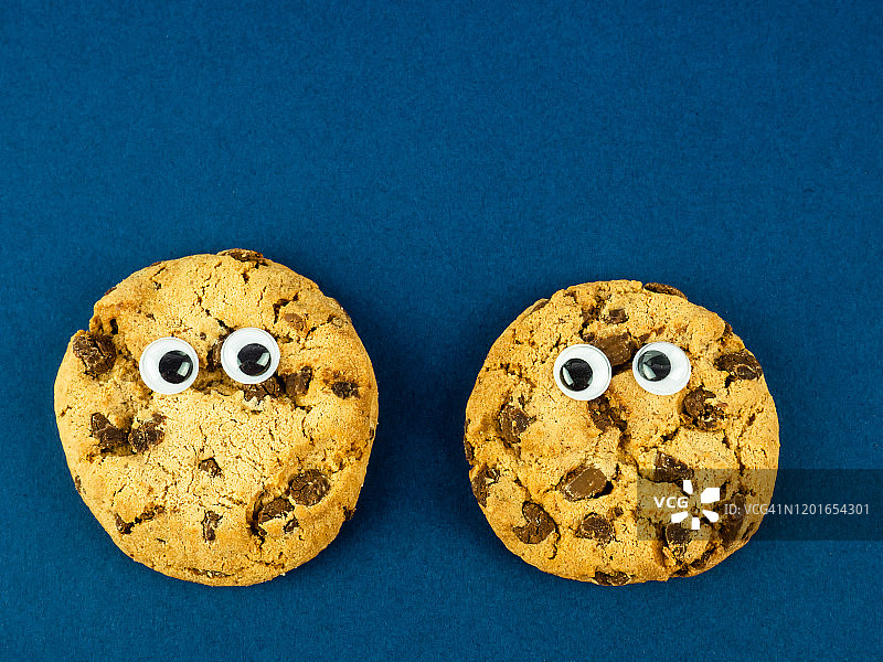 有趣的食物概念：蓝色背景下的两块巧克力饼干图片素材