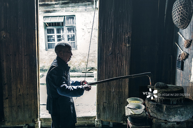 中国年长男性在谷仓里磨谷物图片素材
