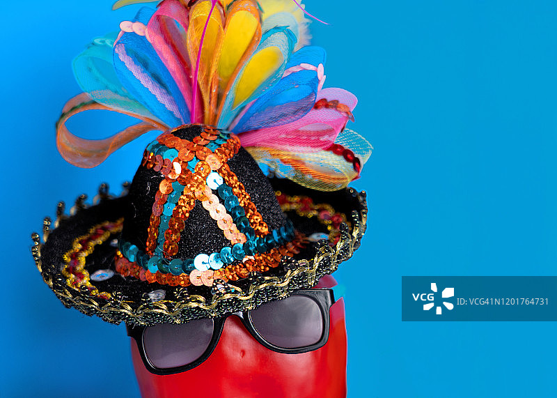 戴太阳镜和帽子的派对红色辣椒（蓝色背景）图片素材