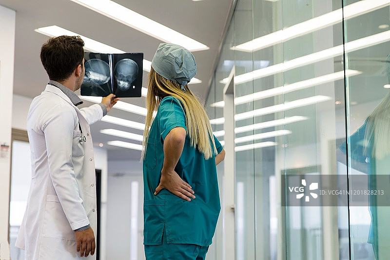 年轻的医护人员正在查看患者的X光头骨片图片素材