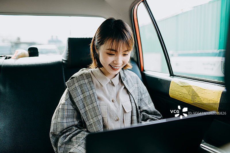 在出租车后座上用笔记本电脑工作的亚洲女商人图片素材