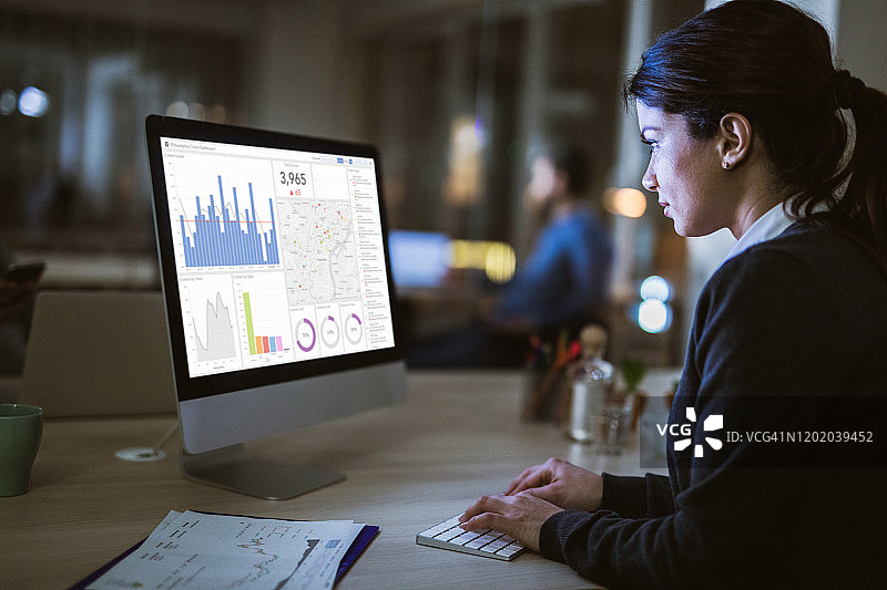 在办公室里分析电脑图表的商务女性侧面照图片素材