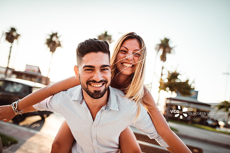 假期黄昏时分，情侣玩骑背图片素材