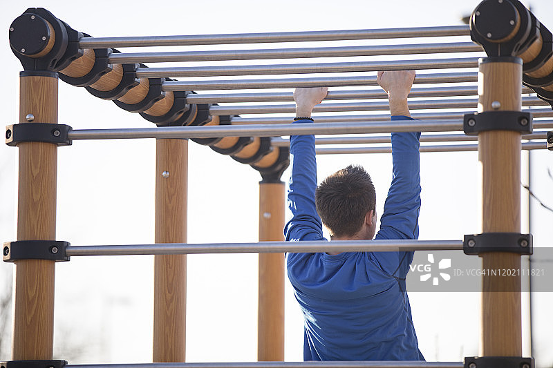 青年男子在街头健身器材上锻炼图片素材