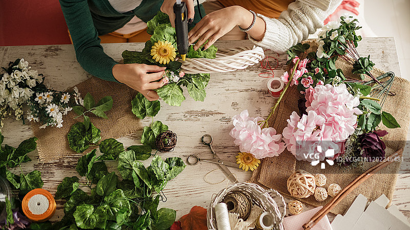 两名年轻女子用热熔胶枪制作美丽的花环图片素材