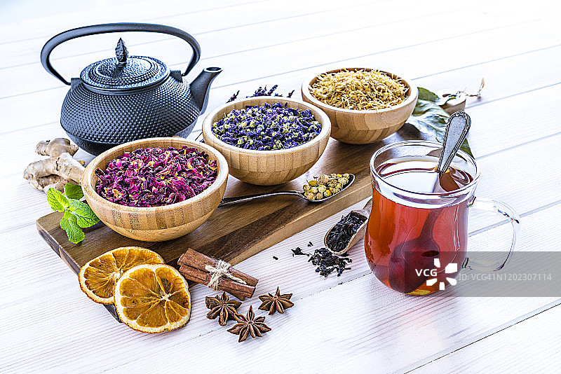 白桌上的草药茶杯，内含干茶叶和花朵图片素材