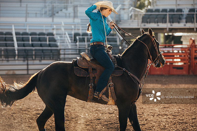 竞技场上，停止赛马后拉缰绳的少女牛仔图片素材