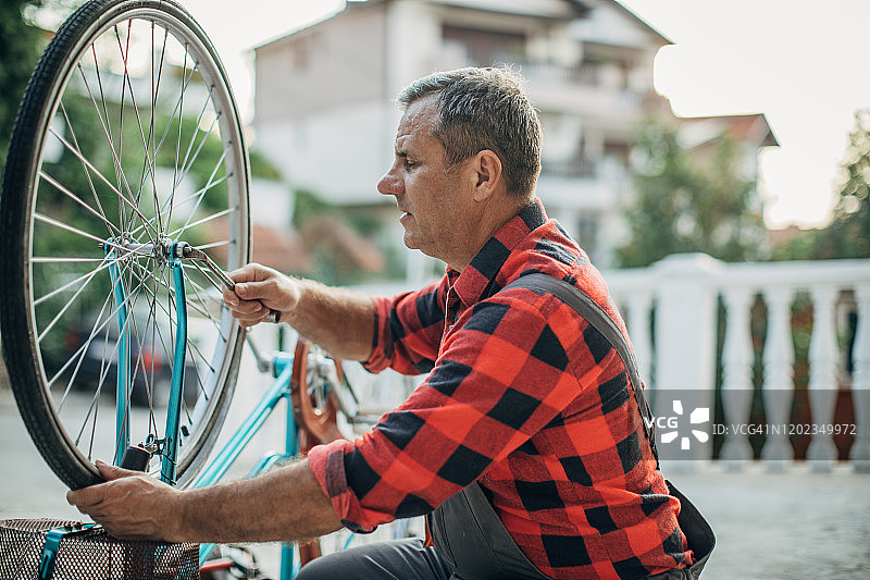 年长的男人在前院修理自行车图片素材