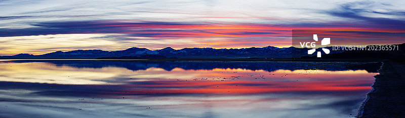 冬季犹他州博纳维尔盐滩日落时分，山脉和天空的倒影全景图片素材