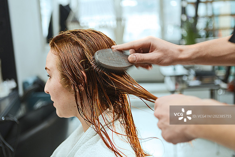 理发师在美发沙龙为红发女子梳头图片素材