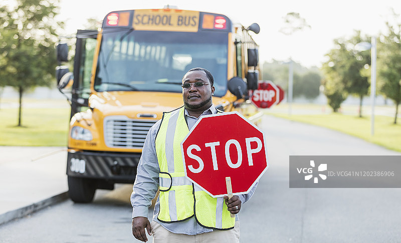 交通管理员站在带有停车标志的校车旁图片素材
