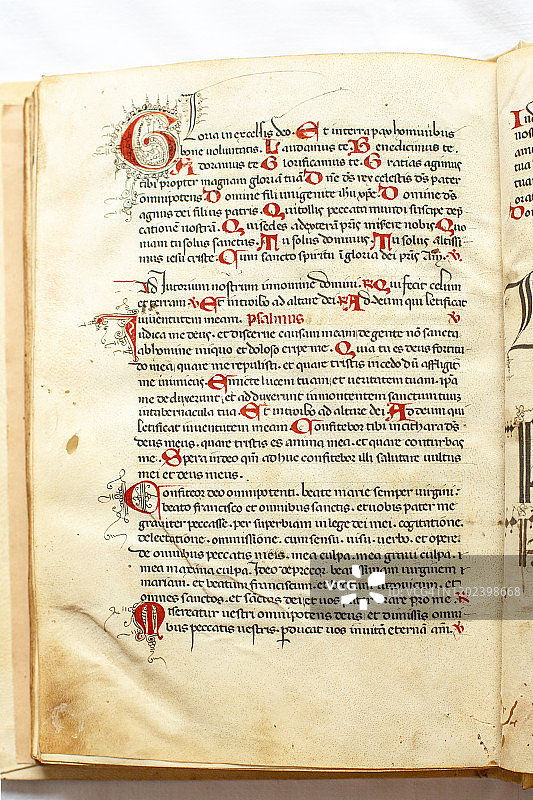 装饰性书法文本页，带有首字下沉和大写字母，并在红色装订的手稿中突出显示其他字母图片素材