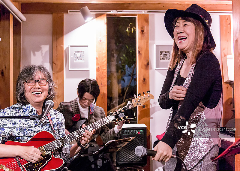 在咖啡馆里唱歌的亚洲老年妇女，表演间隙在交谈图片素材