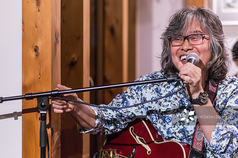 亚洲老年男子在乡村风格的咖啡馆里弹吉他图片素材