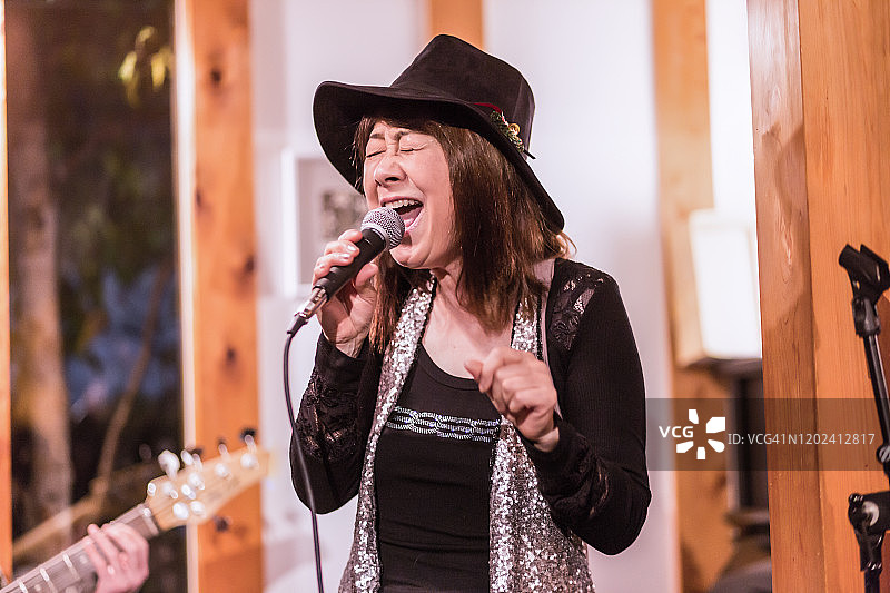 在咖啡馆里唱歌的亚洲老年妇女，表演间隙在交谈图片素材