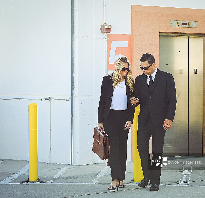 穿着商务装和太阳镜在户外行走的企业商务同事图片素材