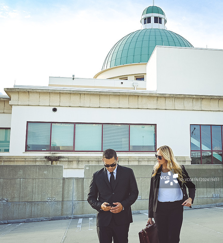 穿着商务装和太阳镜在户外行走的企业商务同事图片素材