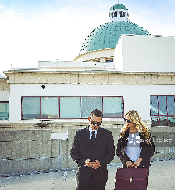 穿着商务装和太阳镜在户外行走的企业商务同事图片素材