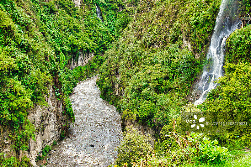 岩石峭壁旁郁郁葱葱的小瀑布和河流图片素材