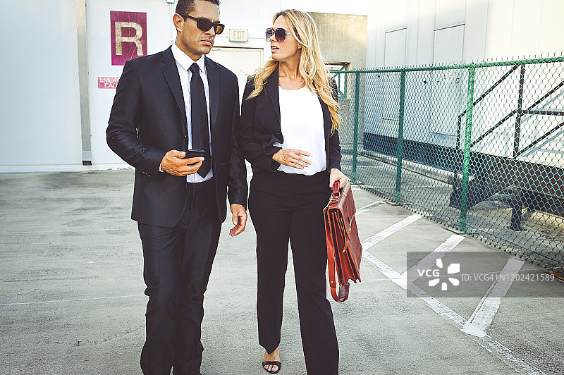穿着商务装和太阳镜在户外行走的企业商务同事图片素材