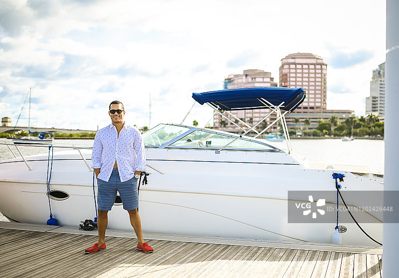 停靠着快艇的船坞上的英俊男人图片素材