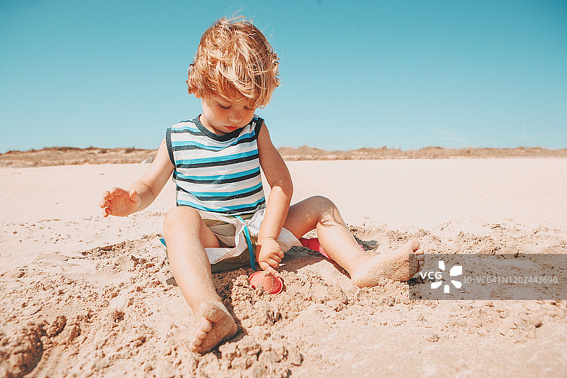 男孩在海滩上堆沙堡图片素材