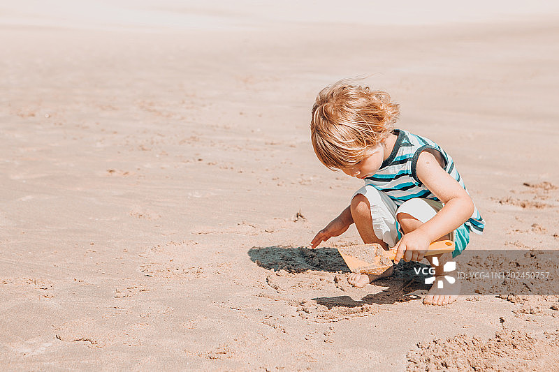 男孩在沙滩上制作沙堡图片素材