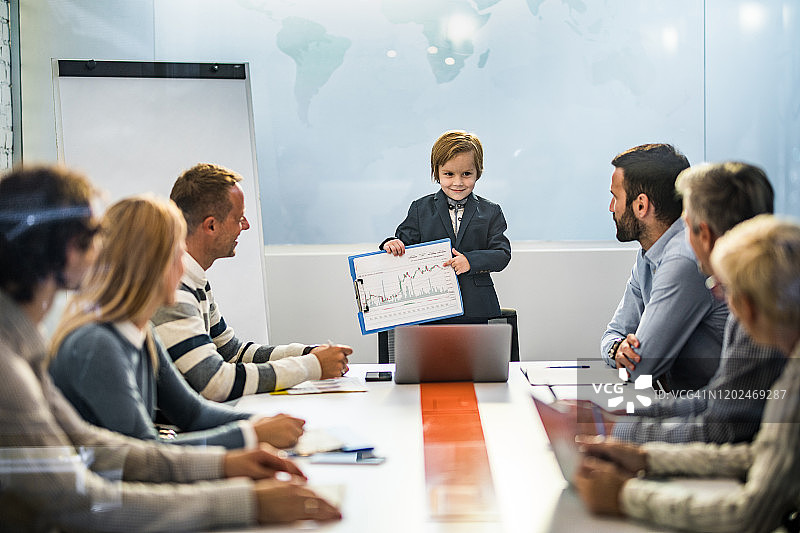 可爱的商务男孩在办公室会议上向他的团队展示业务报告图片素材