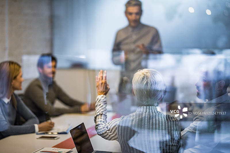 在会议室开会时举手的女商人背影图片素材