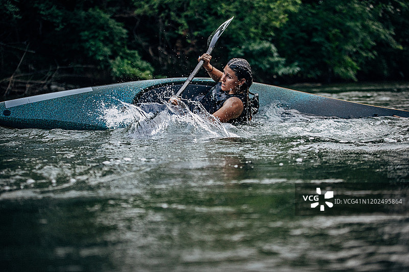 一名女子在山间河流上划皮划艇图片素材