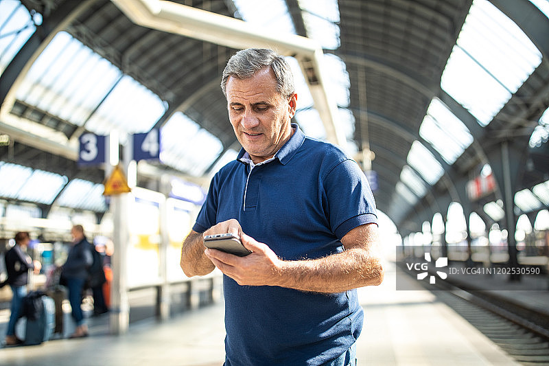 中年男人在科隆中央车站候车时使用手机图片素材