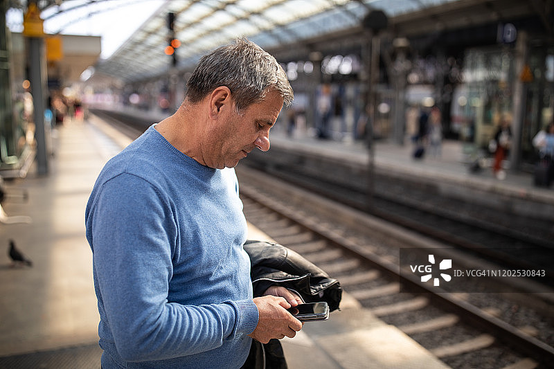 等待火车时发短信的年长游客图片素材