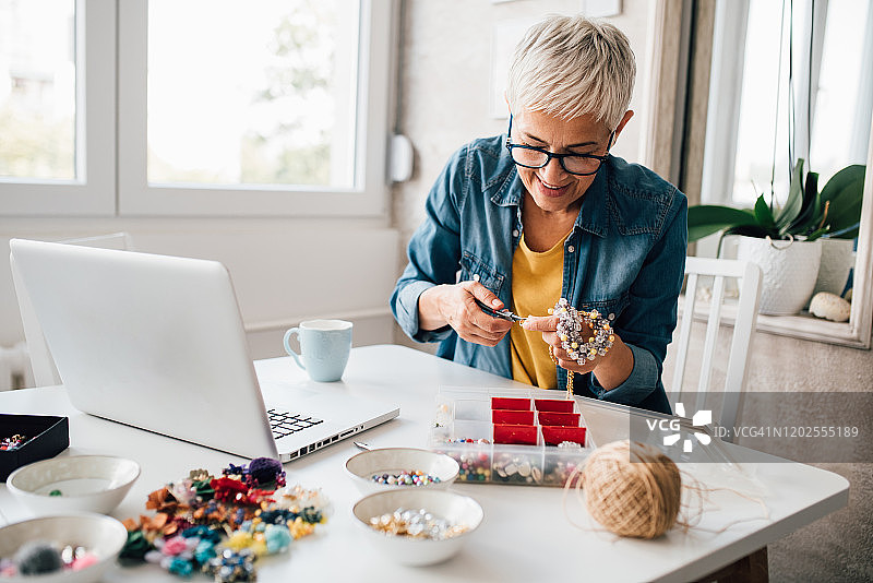 中年妇女观看珠宝制作教程图片素材