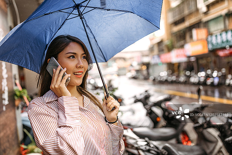 雨天，打伞玩手机的女人图片素材
