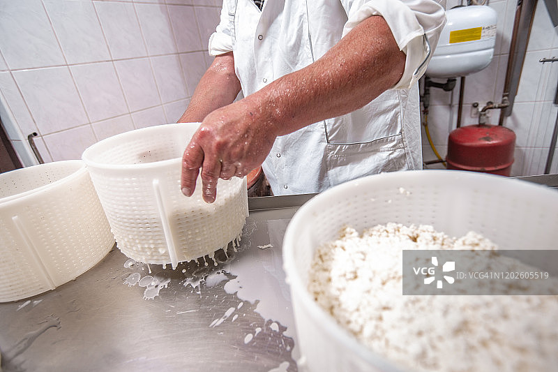 成年男性工人在奶牛场制作羊奶酪图片素材